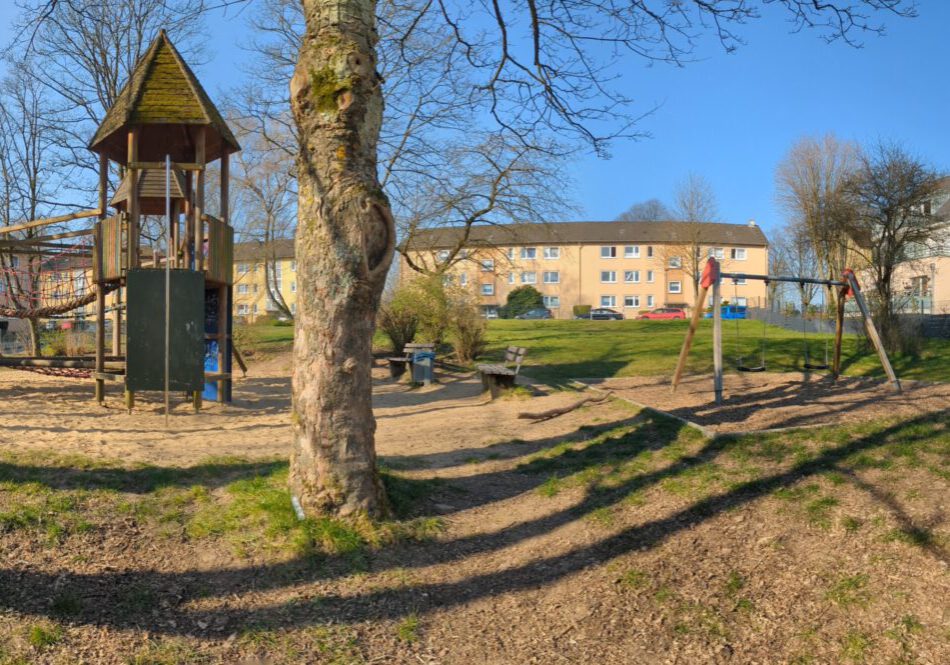 Spielplatz mit Spielgerüst, Schaukel, Rasenfläche und Bänken